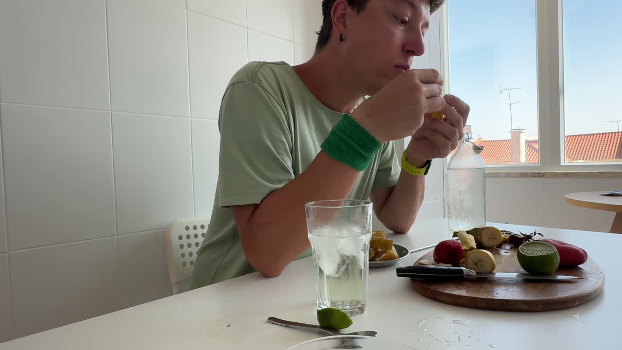 Mann schneidet und isst frische Banane am Küchentisch