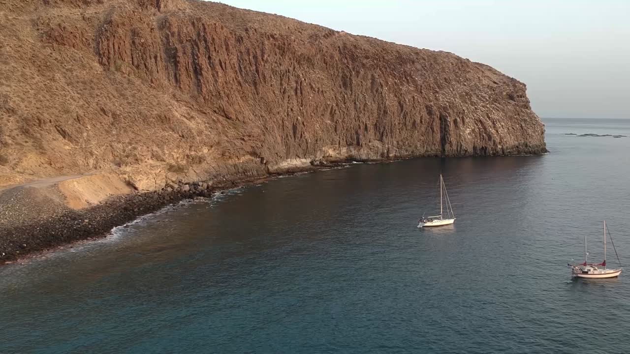acantilado rocoso de la costa de la isla de tenerife con un par de veleros, vista aérea