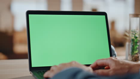 hombre con las manos escribiendo en una computadora portátil de pantalla verde en la oficina. gerente desconocido trabajando