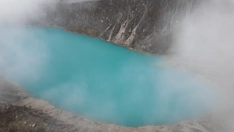 Drone-shot-of-a-turquoise-lake-in-the-middle-of-the-mountains-in-between-the-clouds-in-Huaraz-Peru