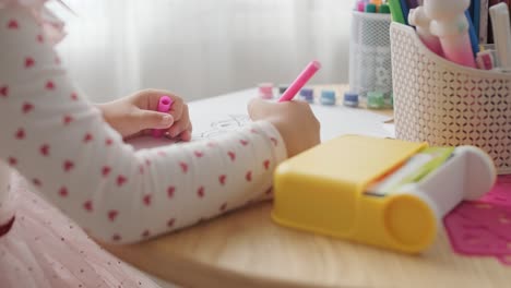 young girl sitting at a table, drawing with colorful crayons. ideal for themes of creativity, childhood development, learning, and art activities in a cozy indoor setting.