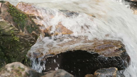 Shallow-depth-of-field,-dolly-side-shot-of-water-flowing-in-springtime-down-a-rapid-stream