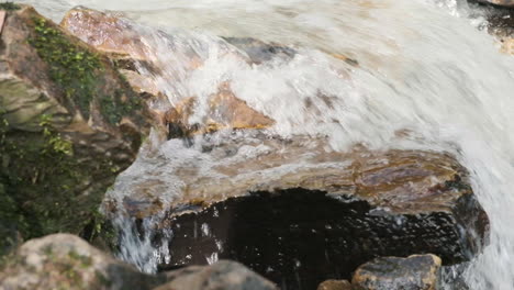 poca profundidad de campo, toma lateral del carro de agua que fluye en primavera por una corriente rápida