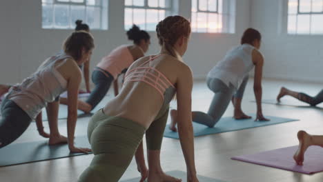 Clase-De-Yoga-De-Mujeres-Sanas-Practicando-Pose-De-Estocada-Baja-En-El-Gimnasio-Al-Amanecer-Disfrutando-Del-Ejercicio-Temprano-En-La-Mañana