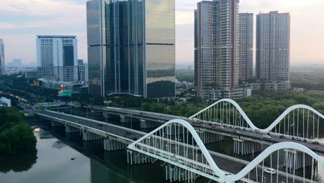 traffic driving on bridge in pik area of jakarta with modern high-rise buildings at dusk
