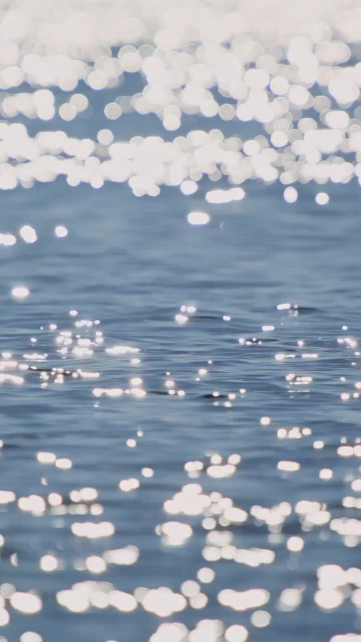 Riflessi scintillanti del sole sulla superficie dell'acqua blu