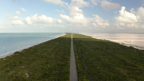 long straight road on grassy isthmus between sea and salt ponds