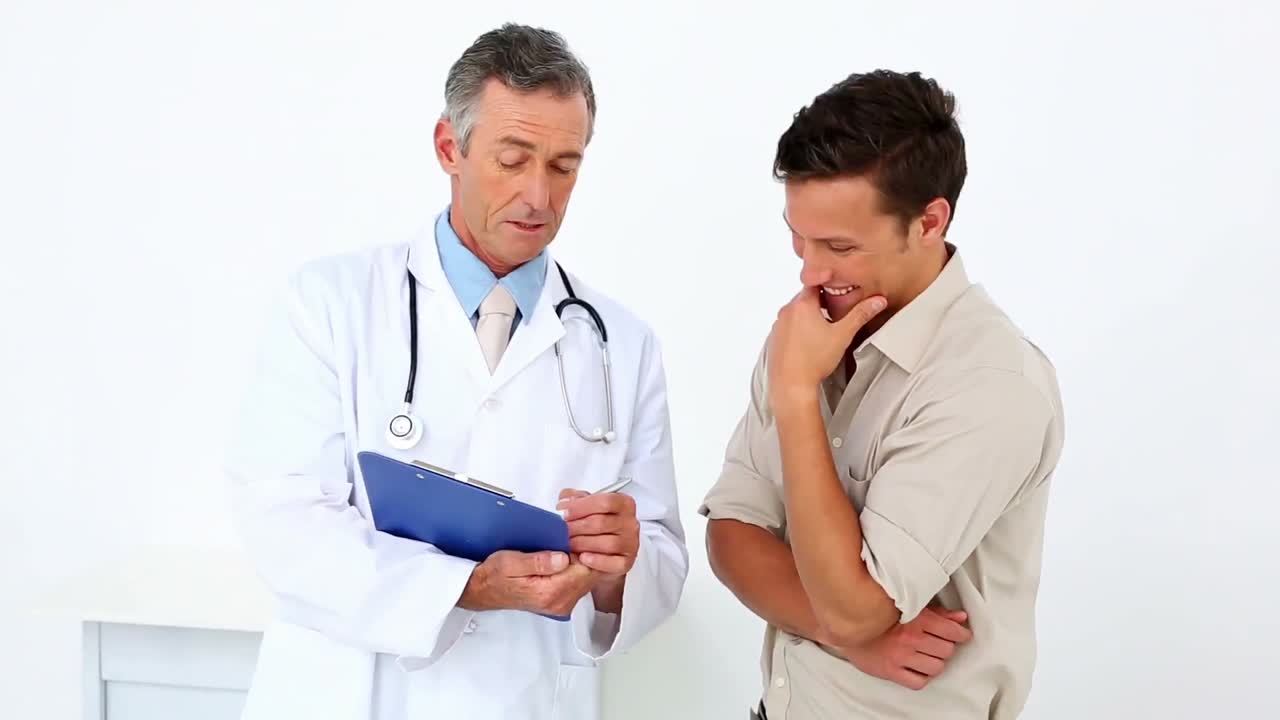 Pasien berbicara dengan dokternya yang memegang papan klip