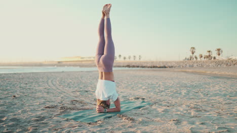 Yogi-Mädchen-Steht-Auf-Dem-Kopf-Und-Macht-Yoga-Posen-Am-Meer.