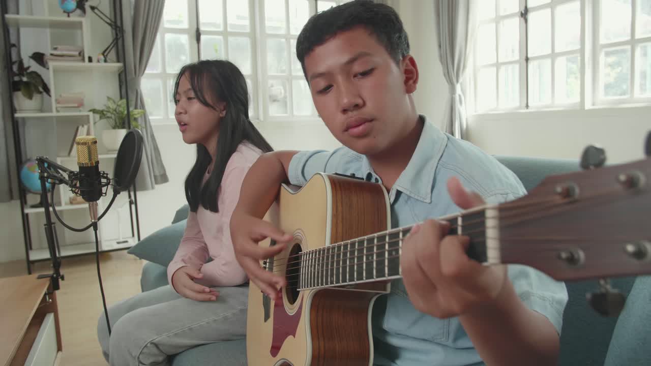 Teenage siblings singing and playing guitar
