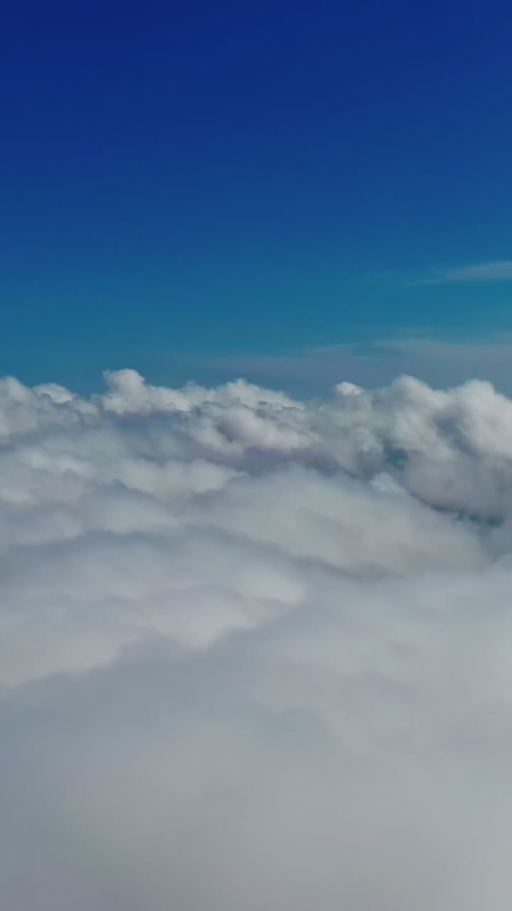 Blue sky and white clouds background. Stunning footage above clouds with blue sky. Travelling by air background. Real time footage. Aerial view. Vertical video