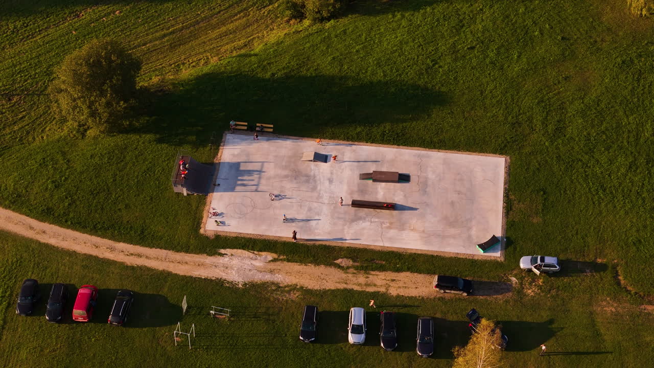 Top-down drone view of people skateboarding at a concrete skatepark in Augsligatne, Latvia.