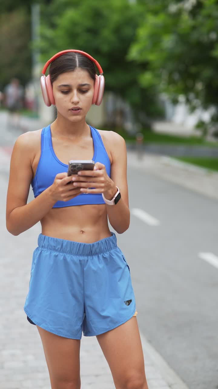 mujer con ropa deportiva usando el teléfono al aire libre