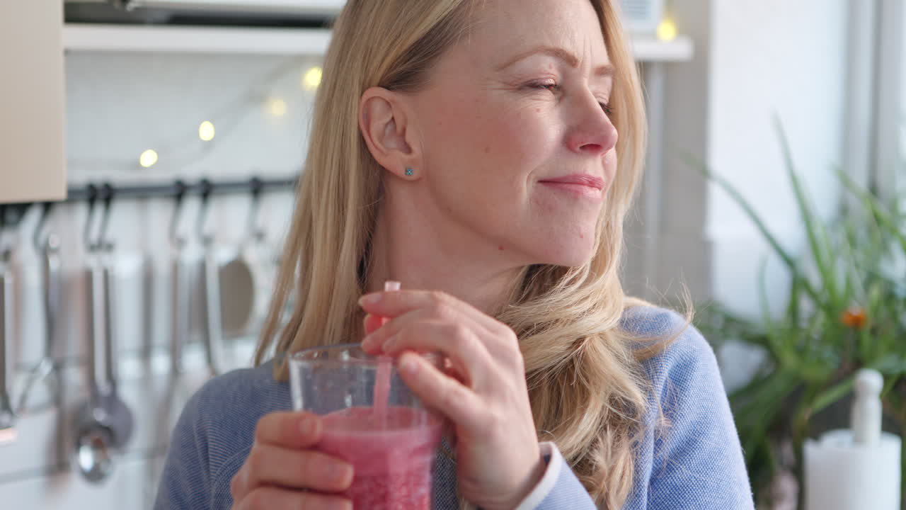 Donna che beve un frullato rosa