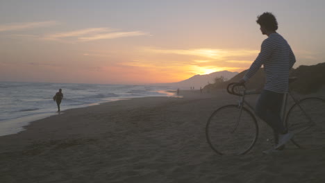 hombre con bicicleta en la playa, hermoso paisaje de puesta de sol