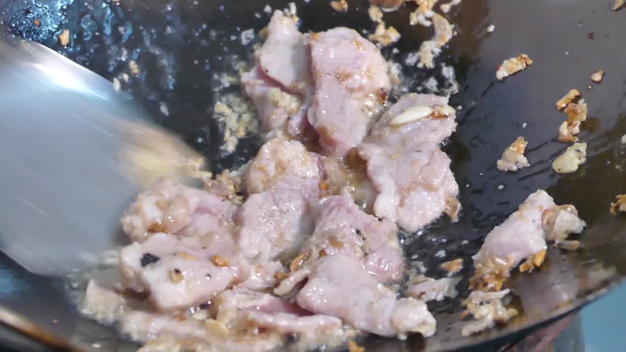 cucinando in padella aglio e pepe di maiale nel wok, primo piano, rallentatore