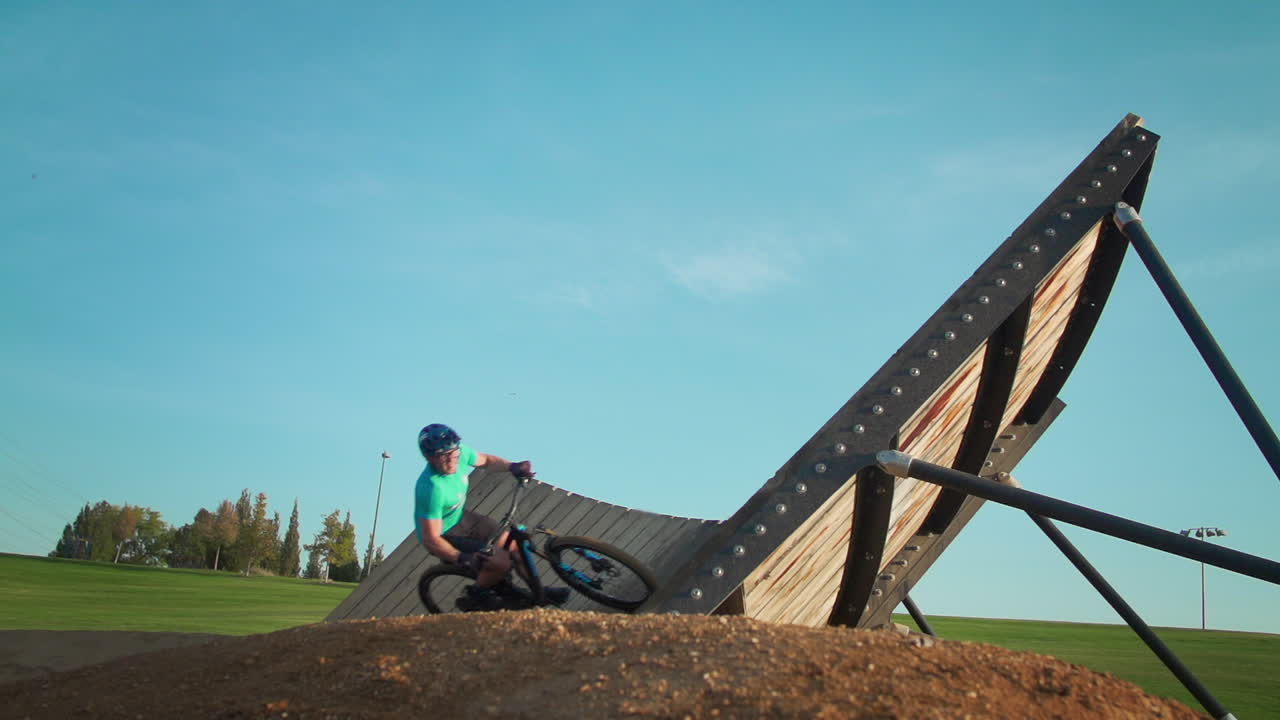 산악자전거를 탄 남자가 자전거 공원에서 나무 경사로를 돌고 공중으로 발사한다