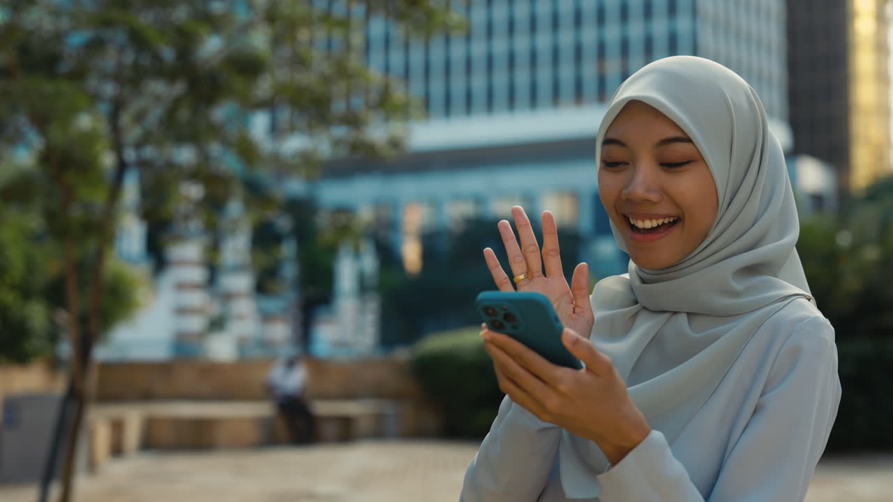 Young Muslim Woman Engaged in Video Call on Smartphone Outdoors