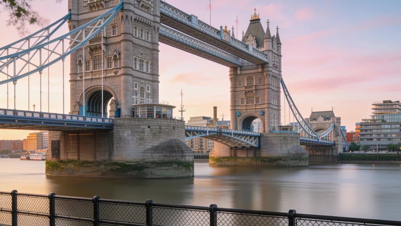 Mostrando a Tower Bridge atravessando o Rio Tâmisa da grade da margem, com a luz do nascer do sol refletindo na água.