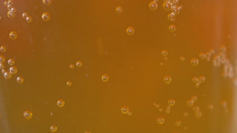 bubbles coming off a smooth surface in an amber beer