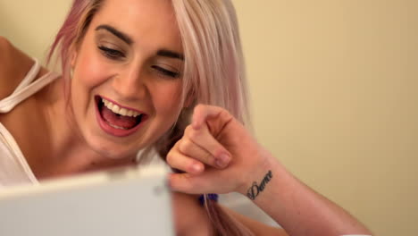 joven rubia muy acostada en la cama usando la tableta