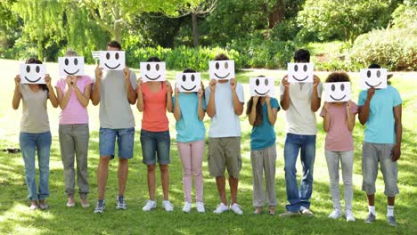 group of casual young friends holding smiley faces over their faces