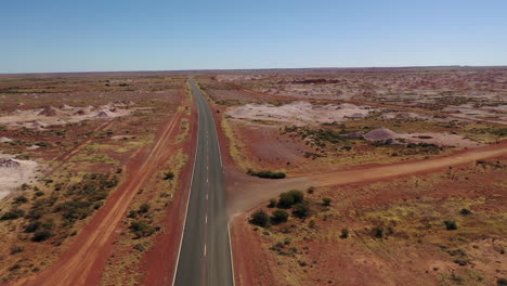 Aerial:-Drone-shot-flying-off-the-main-road-to-reveal-large-scale-opal-mining-fields-in-Coober-Pedy,-South-Australian-Outback