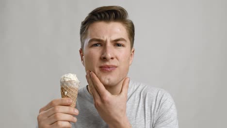 young man experiencing toothache while holding ice cream cone