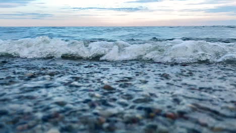 Tiro-En-ángulo-Bajo-De-Las-Olas-Rompiendo-En-La-Orilla-Del-Mar-Durante-El-Día-Después-De-La-Puesta-Del-Sol,-Primer-Plano