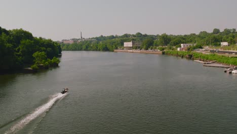 an aerial shot over the river in richmond that follows a boat along the water and goes into the skyline of the city