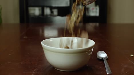 cereal pouring in slow motion from a plastic bag into a white bowl on a table