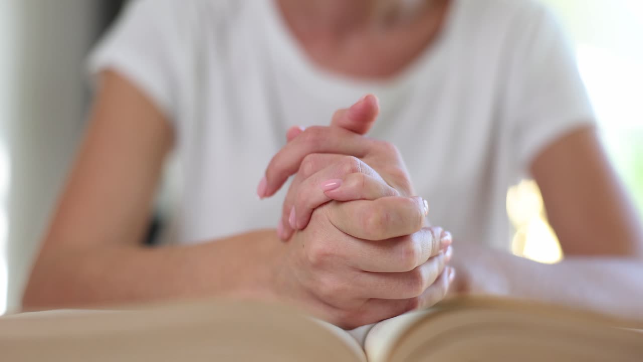 Mani di donna con un libro spesso aperto, pugni stretti sulle pagine