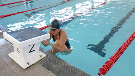 caucasian female swimmer athlete rests at the poolside, with copy space