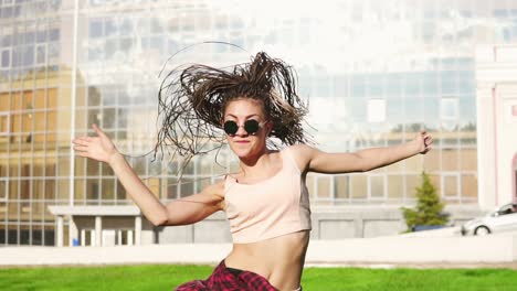 Junges-Schönes-Mädchen-Mit-Dreadlocks,-Das-In-Einem-Park-Tanzt.-Schöne-Frau-In-Jeans-Und-Sonnenbrille,-Die-Musik-Hört-Und-Tanzt