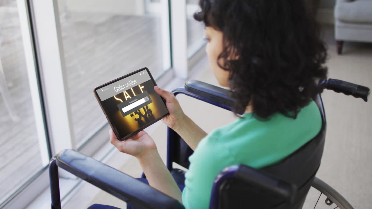 Biracial woman in wheelchair using tablet, online shopping during sale, slow motion