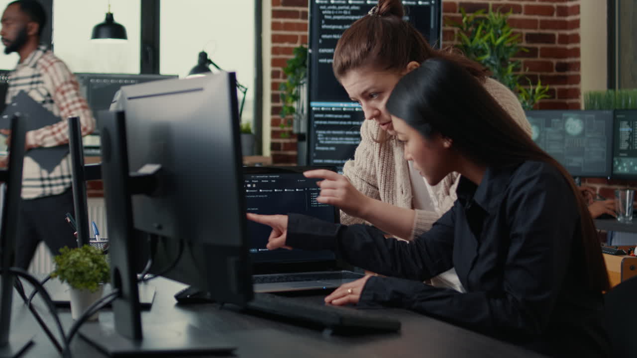 Two software engineers analyzing source code running on laptop screen looking for errors