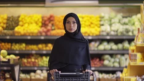 portrait of a muslim woman shopping for groceries at supermarket, push the cart