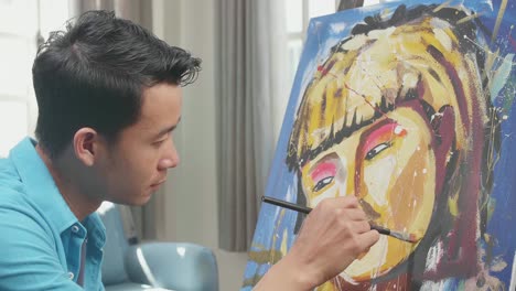 vista lateral de cerca de un artista asiático hombre sosteniendo pincel color mezclado vuelve a sonreír mientras pinta una chica en el lienzo