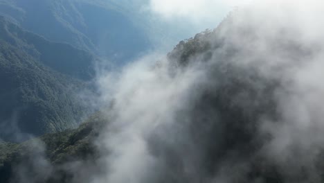 Nature-aerial-flight-through-backlit-cloud-in-steep-jungle-mountain