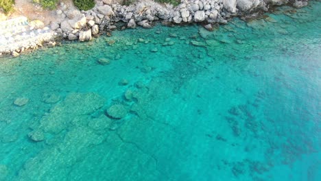 Drone-view-in-Greece-top-view-over-blue-sea-in-Loutro-next-to-a-rocky-hill-on-a-sunny-day