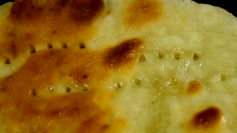 toasted greasy flatbread is fried in cooking oil in pan.