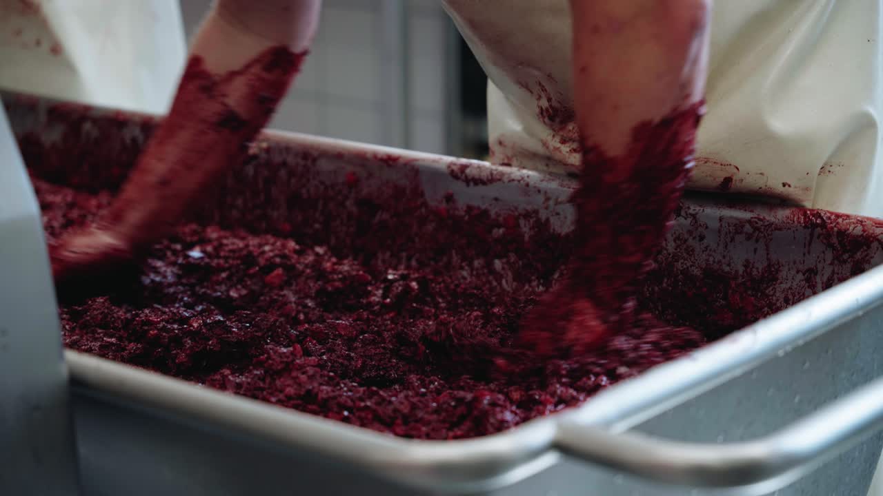 las manos de los carniceros están cubiertas de carne picada de sangre bratwurst mezclándose en un gran tanque de preparación