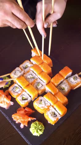 people eating sushi with chopsticks