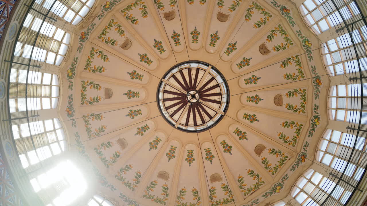 Upward tilt to the painted central dome and skylight, with floral motifs and radial beams at the Central Market of Valencia, Spain