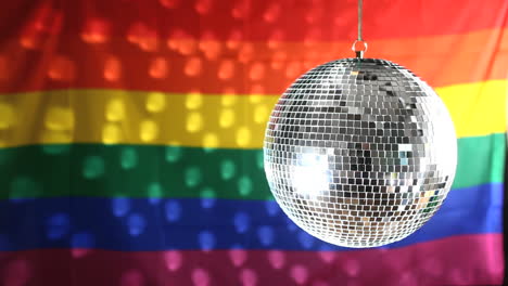 bola de discoteca girando contra la bandera del orgullo gay