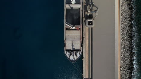 aerial shot over one of the ships that transport the merchandise and the cranes that load the cement