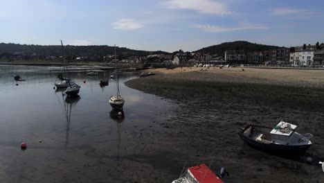 Aerial-view-boats-in-shimmering-low-tide-sunny-warm-Rhos-on-Sea-promenade-sand-beach-marina-low-orbit-right