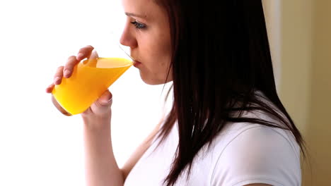 una mujer atractiva bebiendo jugo de naranja.