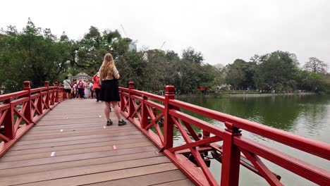 personas caminando por un pintoresco puente rojo