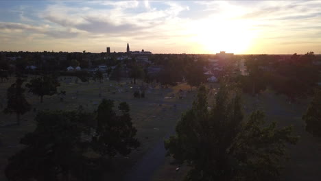 Toma-Aérea-Sobre-Un-Cementerio-En-Georgia-Con-La-Puesta-De-Sol-Detrás